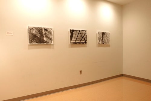 Three black and white photos displayed in an otherwise empty room.