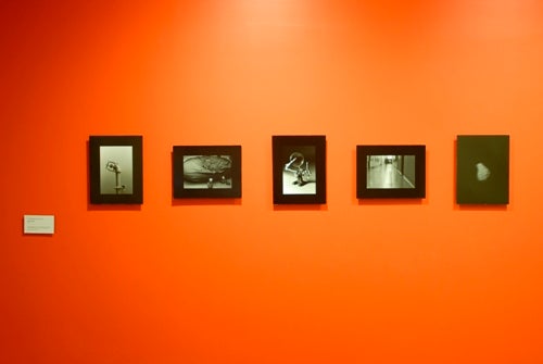 Black-framed photographs on a bright orange wall.