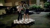 Two people standing and balancing on a wooden platform with hexagonal holes.