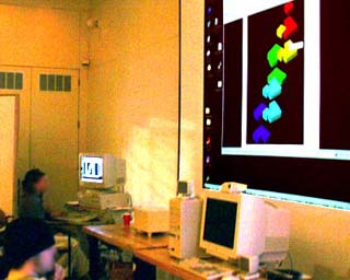 Photo of students seated at computers while watching a projected computer screen displaying their collaborative work with students at Miyagi University in Japan.