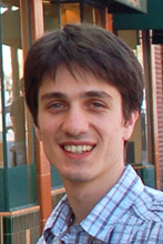 A young man with black hair and a striped shirt stands in the foreground.