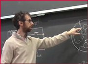 A men standing in front of a blackboard and pointing the blackboard with left hand.