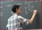 A men standing in front of a blackboard and writing on the blackboard.