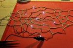 Photo of one of the laser cut fabric pieces, with several small white lights attached to branches.