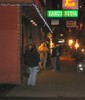 Groups of people standing on a dark street in front of a city cafe