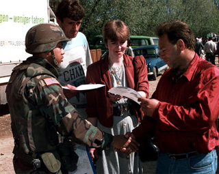 Photogrpah of a U.S. Army soldier greeting local Muslim shoppers.