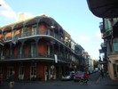 A large three story brick building with large wraparound porches sits on the corner.