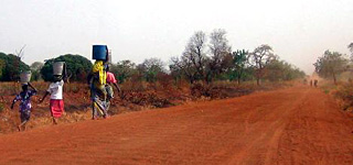 Photograph of women carrying water alongside a road.