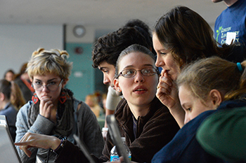 A photo of Kristen Railey surrounded by workshop participants, discussing what they see on a computer monitor.